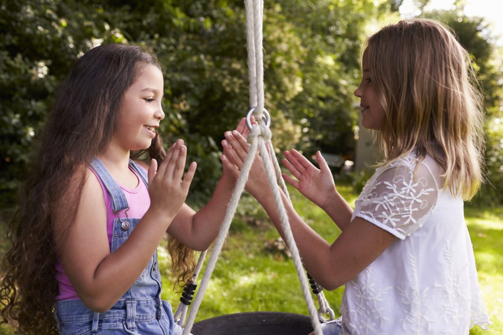 Duas crianças meninas brincando em um balanço de pneu.