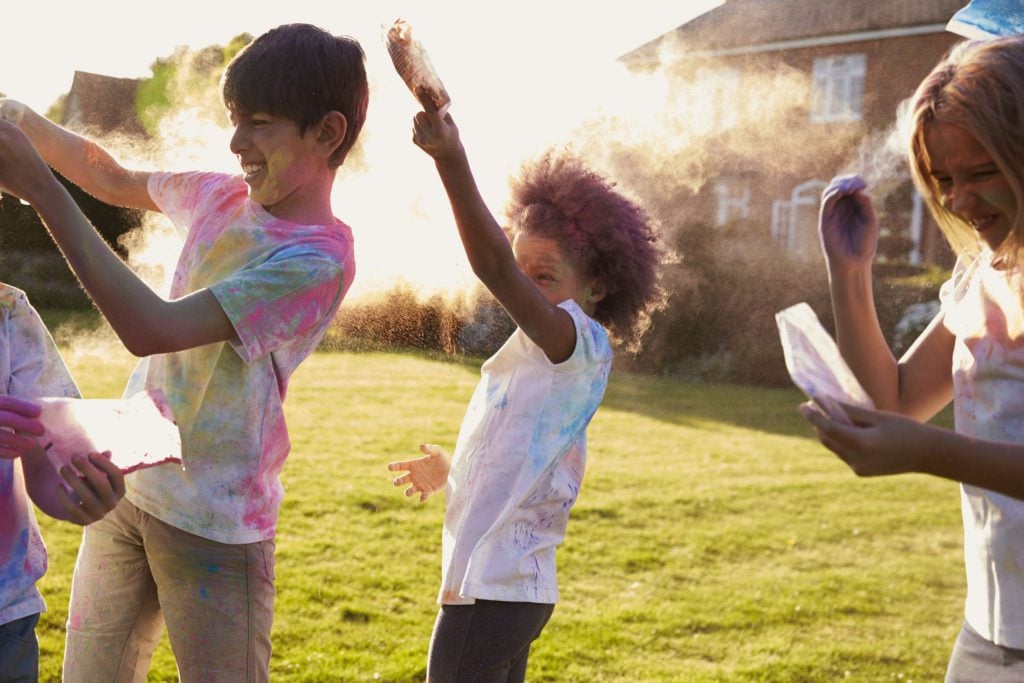 Crianças brincando com pó colorido no quintal.