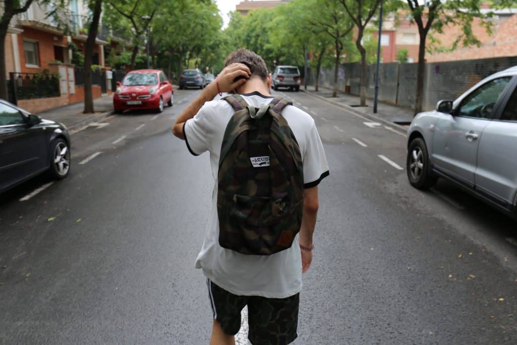 Adolescente andando no meio da rua com a mão na cabeça