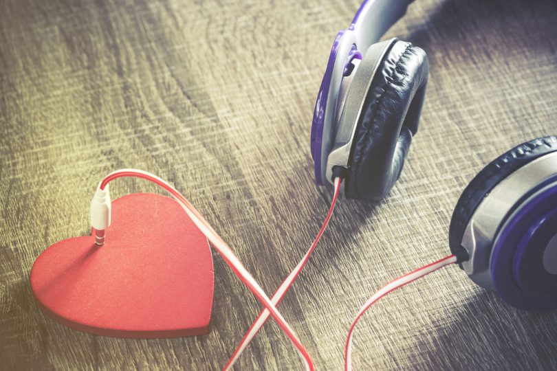 Fones de ouvido em cima de uma mesa, conectado à um coração.