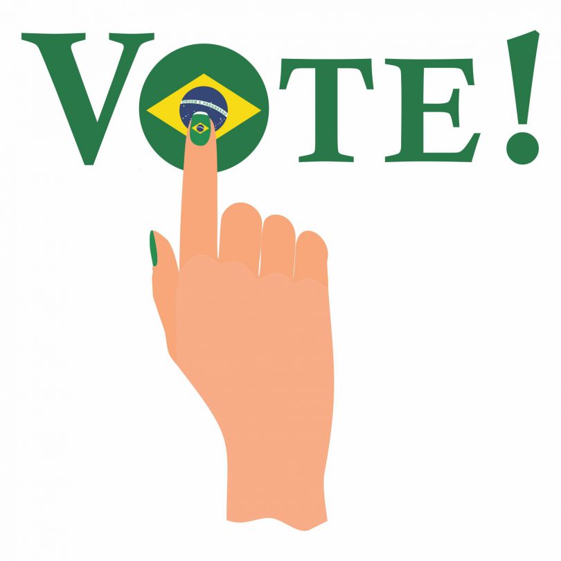 Desenho de uma mão apertando a palavra voto pintada com a bandeira do brasil.