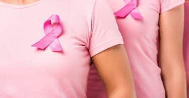 Mulheres usando camiseta rosa e laço simbolizando o Outubro Rosa