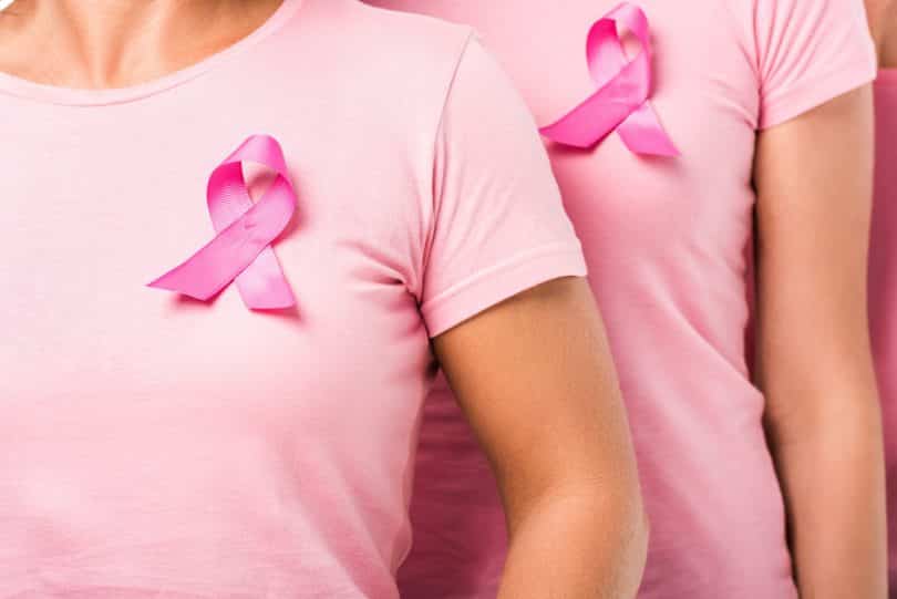 Mulheres usando camiseta rosa e laço simbolizando o Outubro Rosa