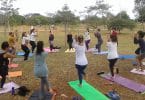 Grupo de pessoas em um parque, organizadas em circulo, praticando ioga.