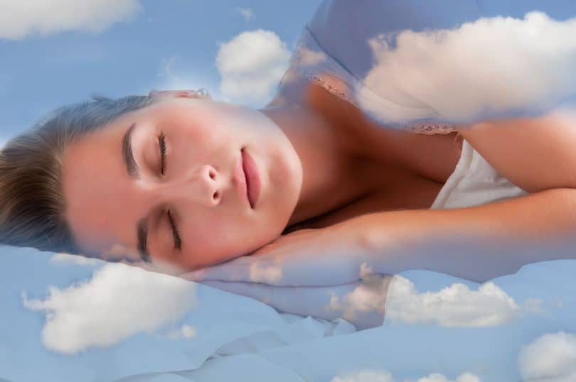 Mulher dormindo em uma cama azul claro de nuvens.