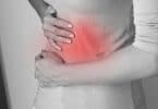 imagem em preto e branco de um abdômen feminino encolhido de dor, com um ponto vermelho, sinalizando o local da dor.