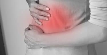 imagem em preto e branco de um abdômen feminino encolhido de dor, com um ponto vermelho, sinalizando o local da dor.