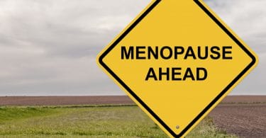 Placa de trânsito escrito: Menopausa à frente, em inglês.