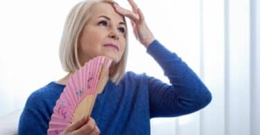 Imagem de uma mulher na menopausa se abanando com um leque