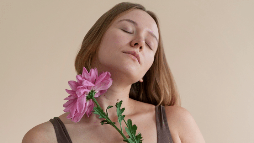 Mulher de olhos fechados segurando uma flor