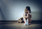 Menina sentada na parede de um corredor chorando