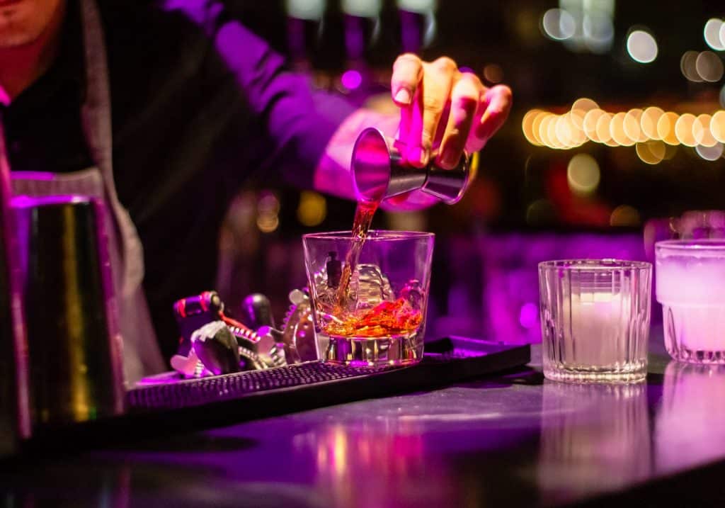 Bartender despejando em um copo uma dose de bebida alcoólica destilada.