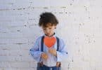 Criança segurando uma plaquinha de coração
