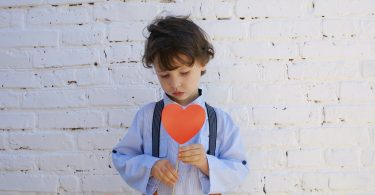 Criança segurando uma plaquinha de coração