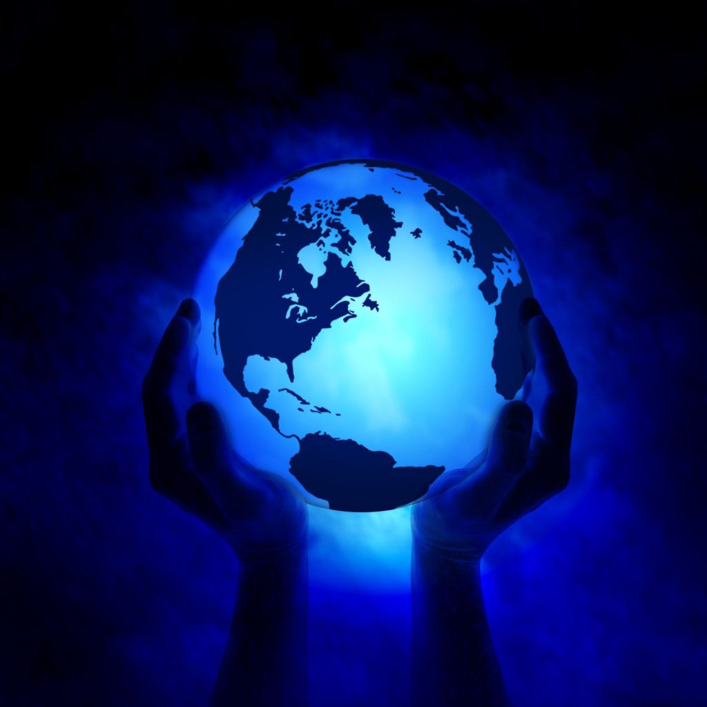 Duas mãos segurando um globo terrestre iluminado de azul.
