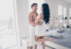 Homem e mulher abraçados com toalhas de banho cobrindo seus corpos.