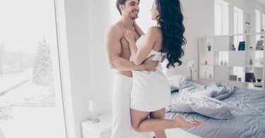 Homem e mulher abraçados com toalhas de banho cobrindo seus corpos.