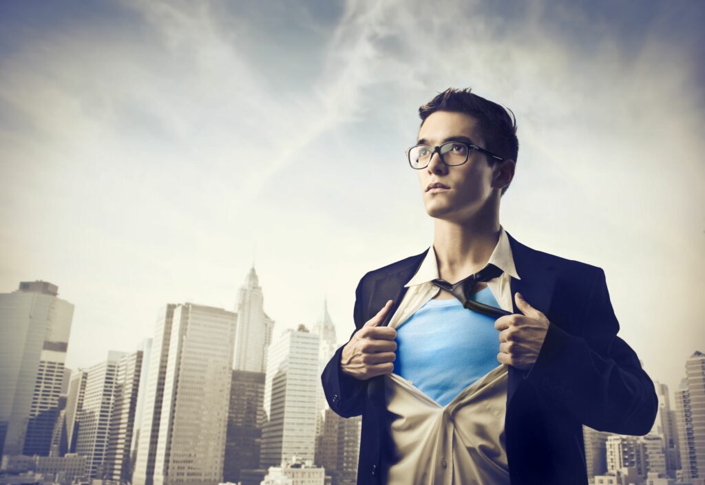 Homem abrindo a camisa do terno e embaixo está usando uma roupa de super-herói.