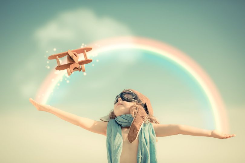 garoto feliz jogando com avião de brinquedo contra o fundo do céu de verão