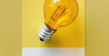 Foto de lampada laranja com fundo amarelo pendurada em parede amarela.