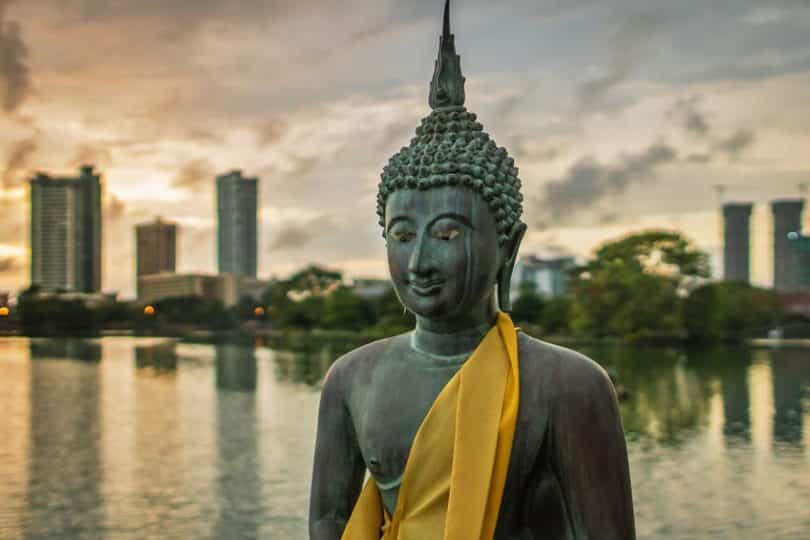 Estátua de Buda com lago e prédios ao fundo