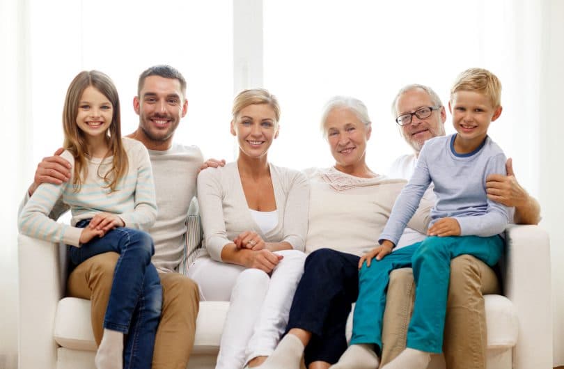 Família reunida num sofá. Avós, filha ou filho, nora ou genro e netos.