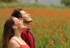 Casal respirando ar puro em um campo cheio de rosas vermelhas.