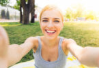 Mulher jovem sorridente fazendo selfie foto no parque.