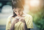 Menina asiática mexendo no celular com cara de séria.