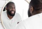 Homem negro se olhando no espelho e sorrindo