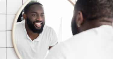 Homem negro se olhando no espelho e sorrindo