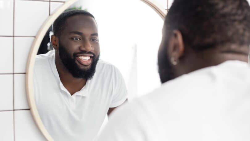 Homem negro se olhando no espelho e sorrindo