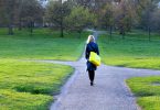 Mulher caminhando em uma estrada que está se dividindo em três novos caminhos.