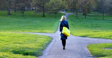 Mulher caminhando em uma estrada que está se dividindo em três novos caminhos.