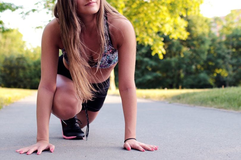 Mulher agachada em posição de largada de corrida