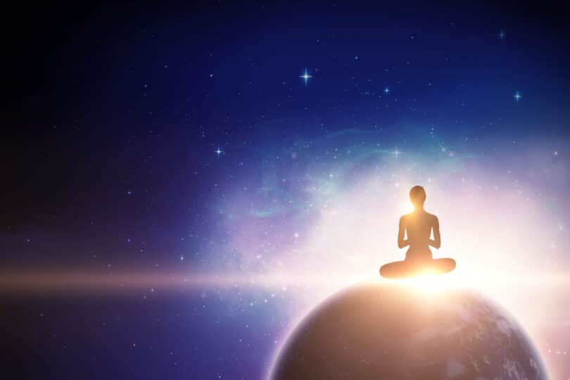 Pessoa meditando em cima do planeta Terra. De dentro dela, sai uma luz
