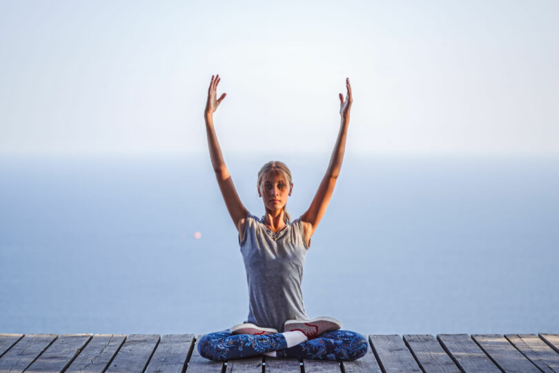 Menina em posição de lotus fazendo yoga.