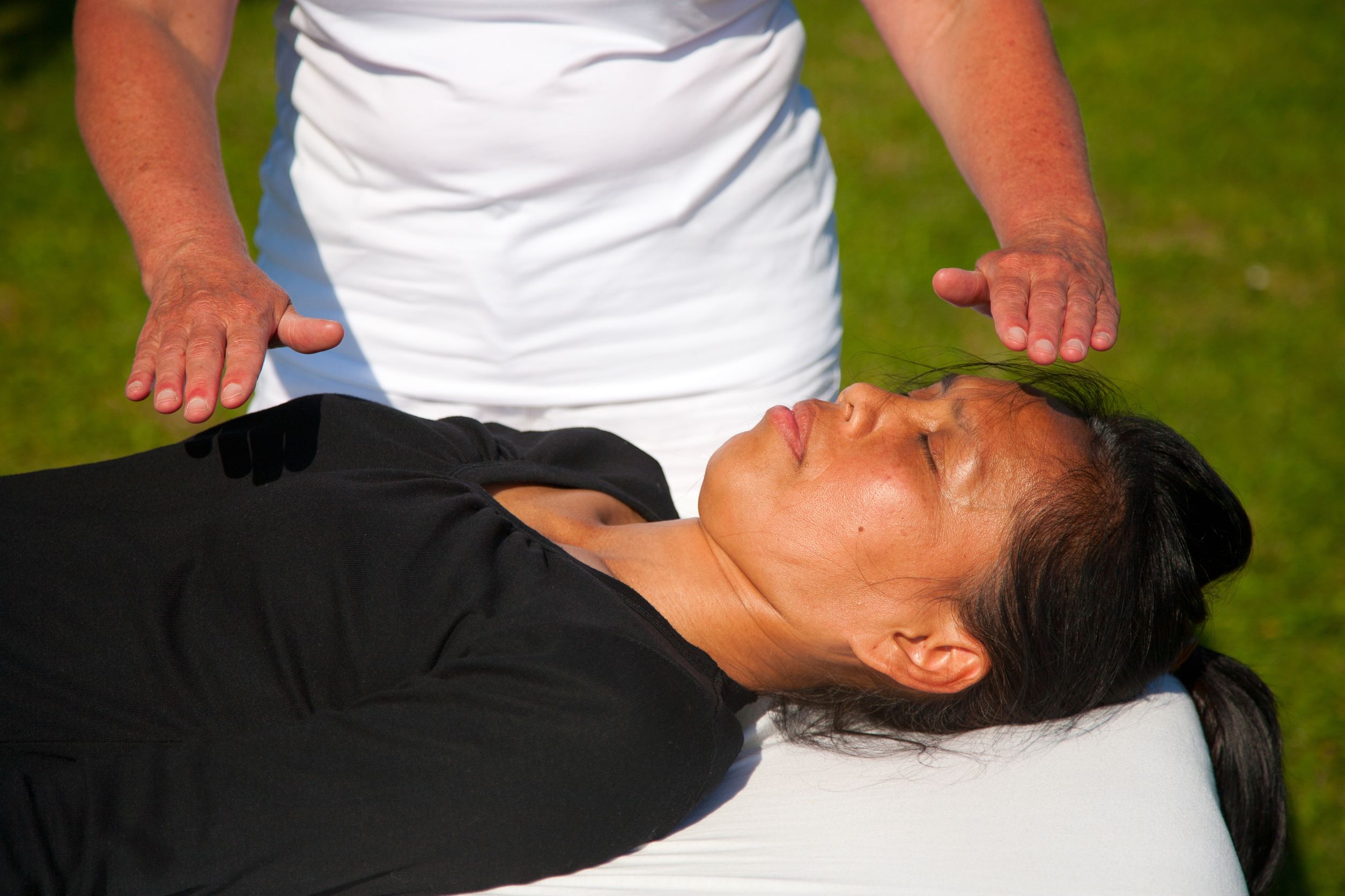Quiropraxia Indiana Mulher com descendência indígena deitada com os olhos fechados em uma maca recebendo uma massagem energética.
