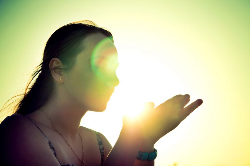 Silhueta de uma mulher segurando raios de sol.