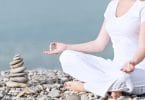 mão de uma mulher meditando em uma pose de ioga na praia