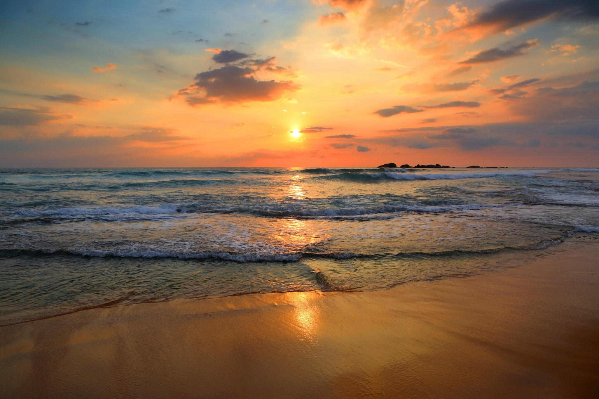 Praia no por do sol o céu está com tons de azul e laranja.