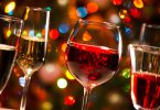 Taças de cristal de vinho e de champanhe no fundo de luzes de Natal.