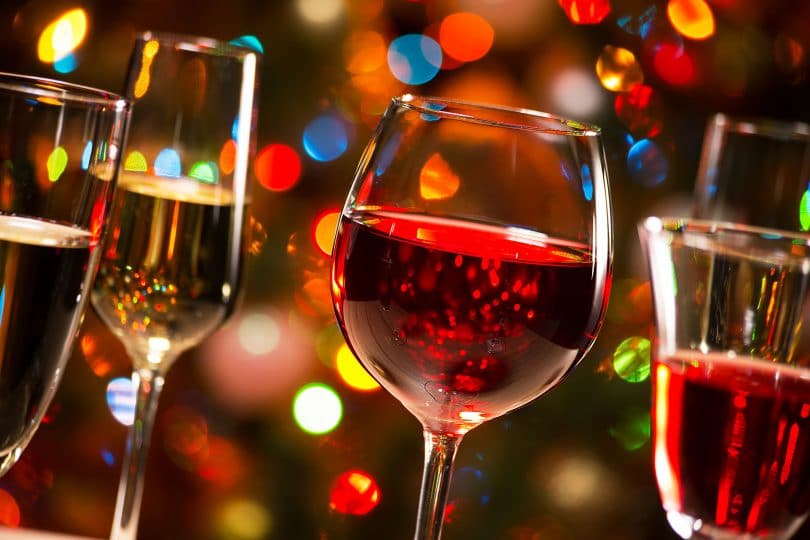 Taças de cristal de vinho e de champanhe no fundo de luzes de Natal.