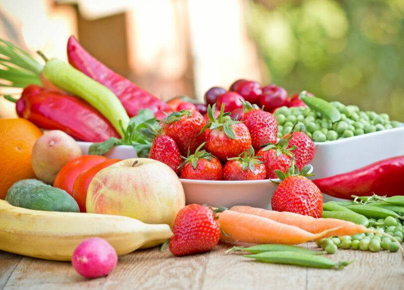 Frutas e verduras naturais em cima de uma mesa de madeira.