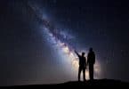 Silhueta de um pai e um filho que apontam o dedo no céu estrelado da noite no fundo da Via Látea.