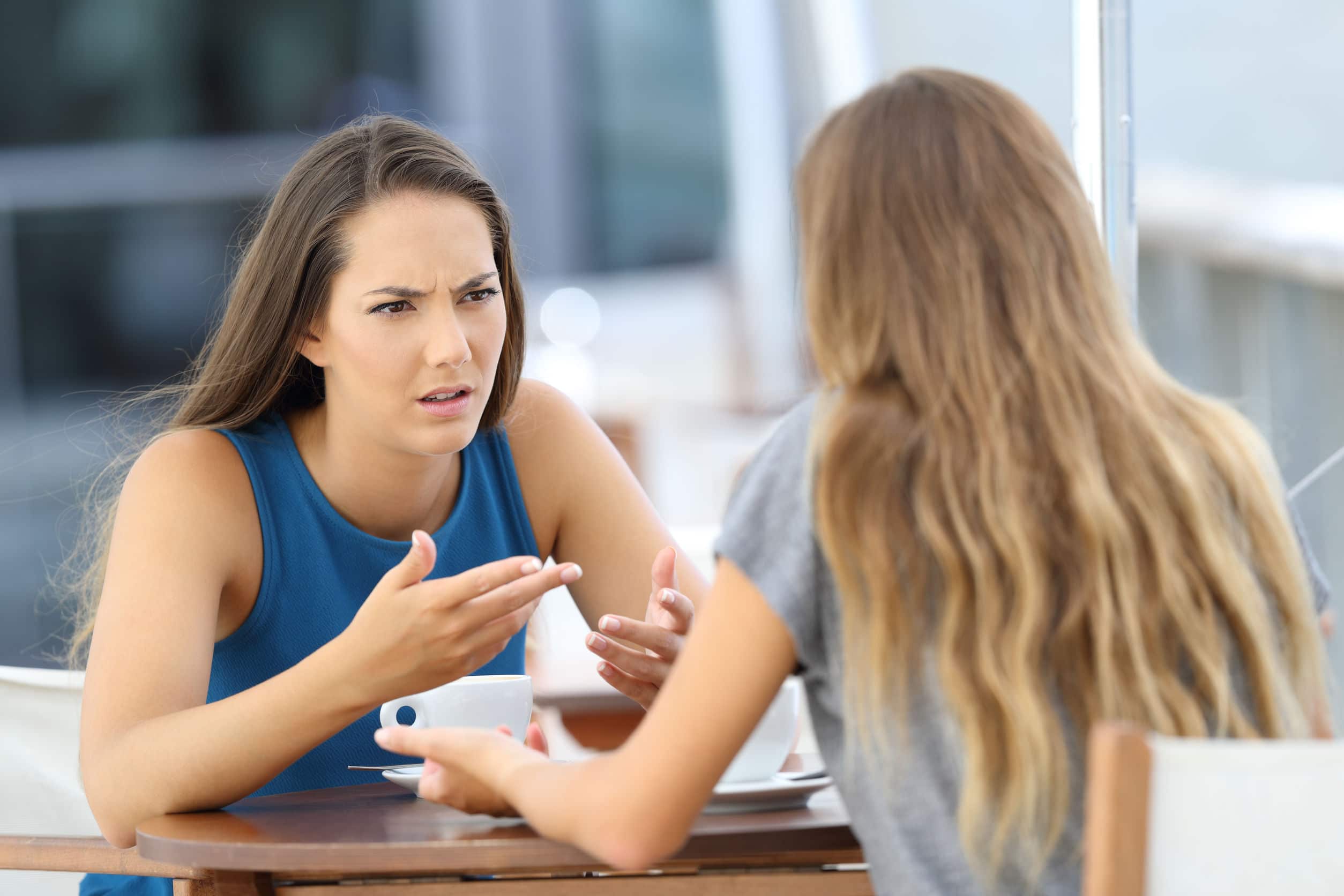 Duas garotas com raiva falando seriamente sentadas em um café