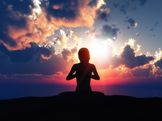 Silhueta de uma mulher em posição meditativa com fundo de nuvens ao anoitecer.