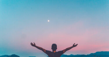 Homem com as mãos levantadas para o céu.