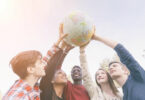 Grupo de jovens segurando o globo do mundo para cima.