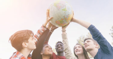 Grupo de jovens segurando o globo do mundo para cima.